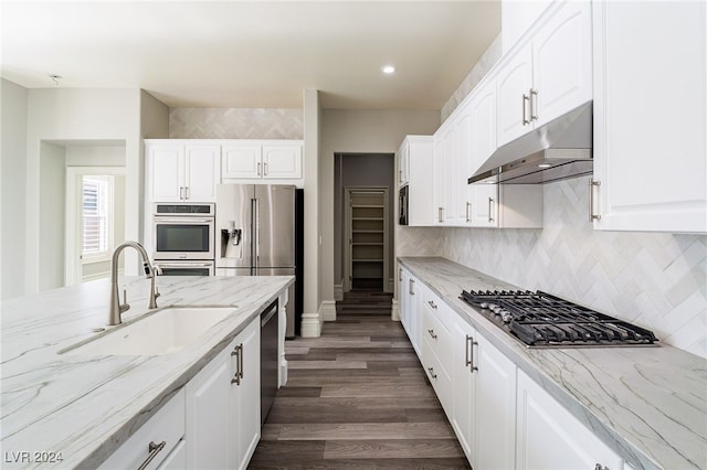 kitchen with stainless steel appliances, dark wood-type flooring, light stone counters, sink, and white cabinetry