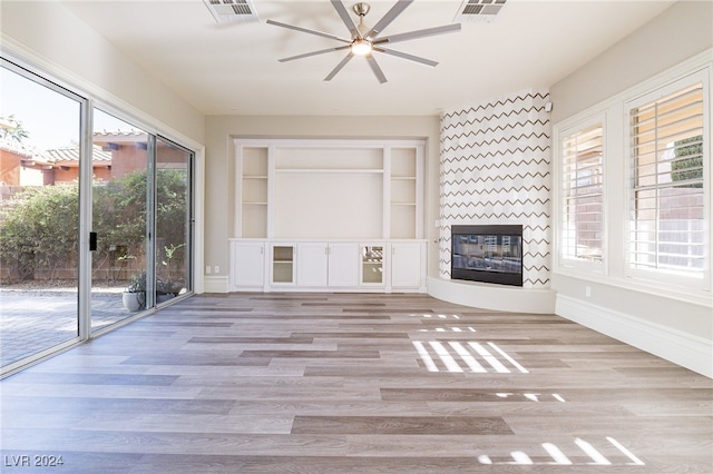 unfurnished living room featuring a fireplace, light hardwood / wood-style flooring, a healthy amount of sunlight, and ceiling fan