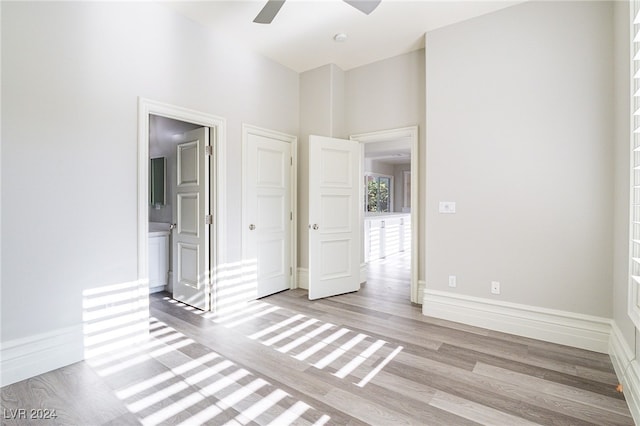 empty room with a towering ceiling, light wood-type flooring, and ceiling fan