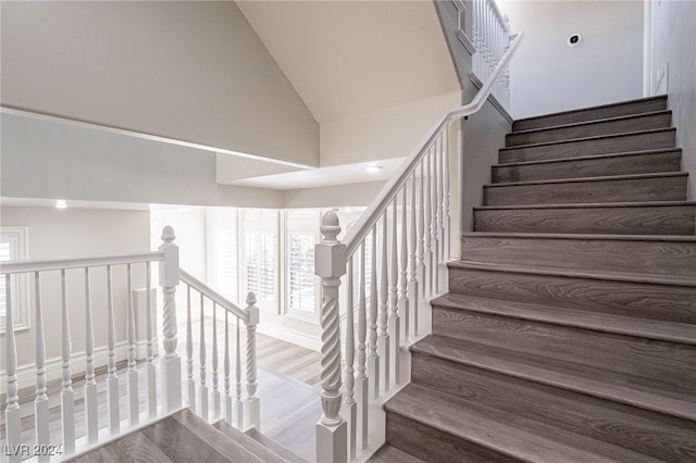 stairway featuring hardwood / wood-style flooring and high vaulted ceiling