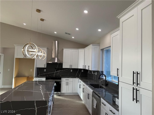 kitchen featuring wall chimney exhaust hood, pendant lighting, a center island, dark stone countertops, and sink