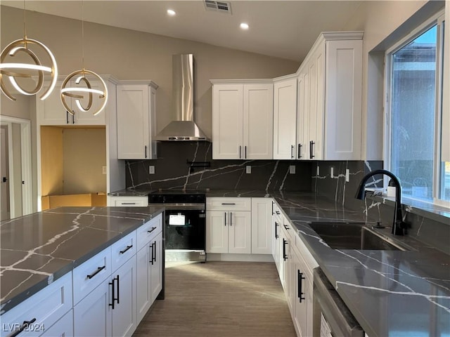 kitchen featuring electric stove, white cabinetry, wall chimney range hood, and hanging light fixtures