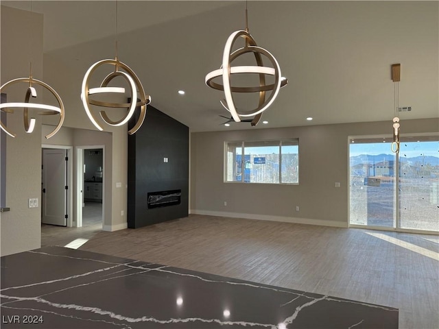 unfurnished living room with lofted ceiling, wood-type flooring, an inviting chandelier, and a large fireplace