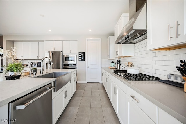 kitchen with stainless steel appliances, sink, decorative backsplash, white cabinets, and wall chimney exhaust hood