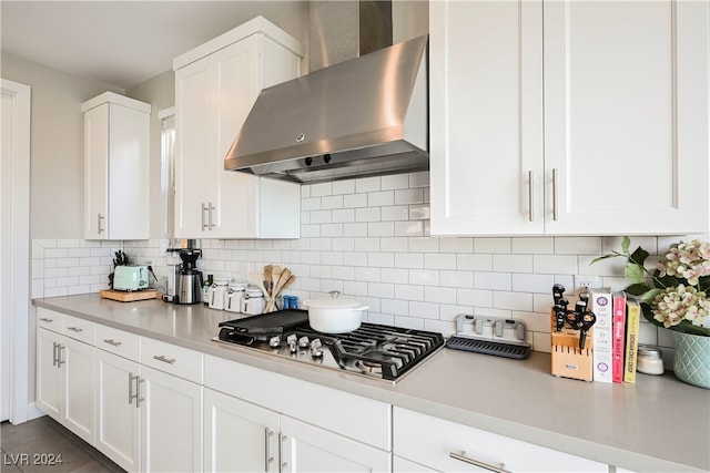 kitchen featuring white cabinetry, wall chimney range hood, backsplash, and stainless steel gas stovetop