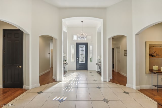 foyer featuring light hardwood / wood-style floors, an inviting chandelier, and a towering ceiling