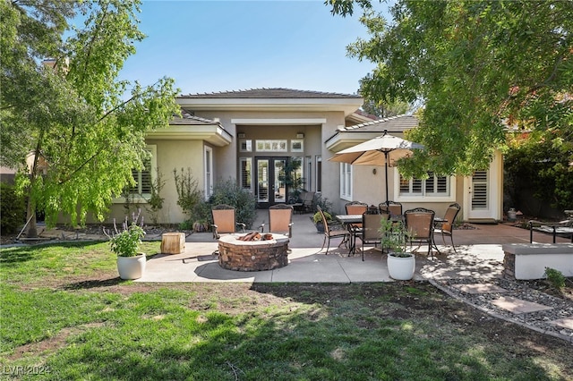 back of property with a patio, an outdoor fire pit, and a lawn