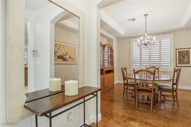 dining space featuring a tray ceiling, an inviting chandelier, and dark hardwood / wood-style flooring