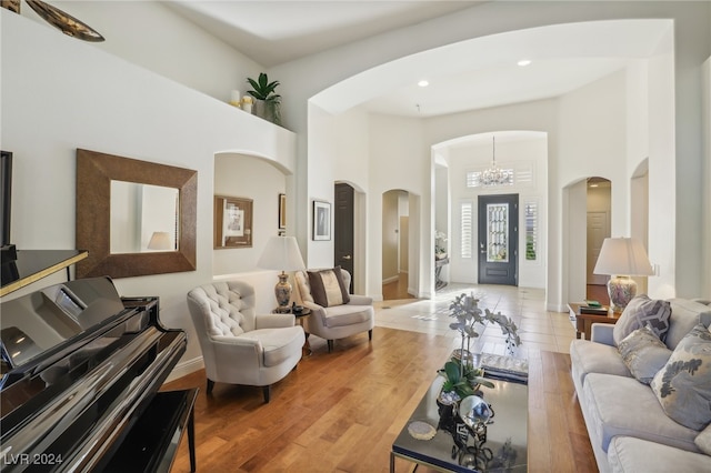 living room with light hardwood / wood-style floors, a chandelier, and a high ceiling