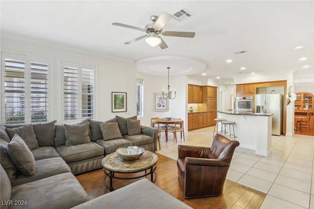 living room featuring crown molding, light tile patterned flooring, and ceiling fan with notable chandelier