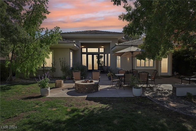 back house at dusk with a yard, an outdoor fire pit, and a patio area