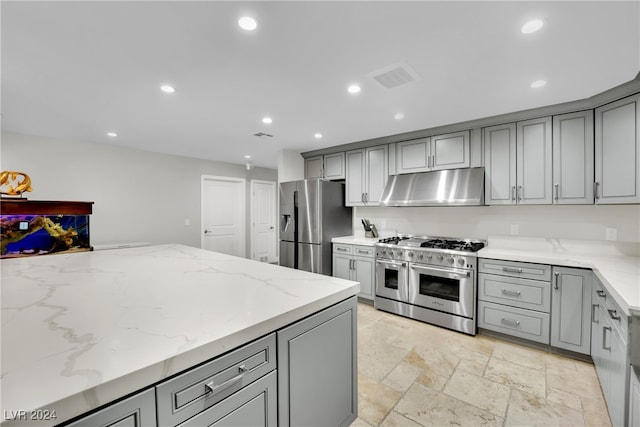 kitchen with gray cabinetry, extractor fan, light stone countertops, and stainless steel appliances