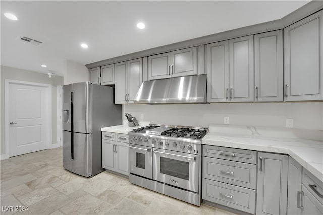 kitchen featuring gray cabinets, ventilation hood, light stone counters, and stainless steel appliances