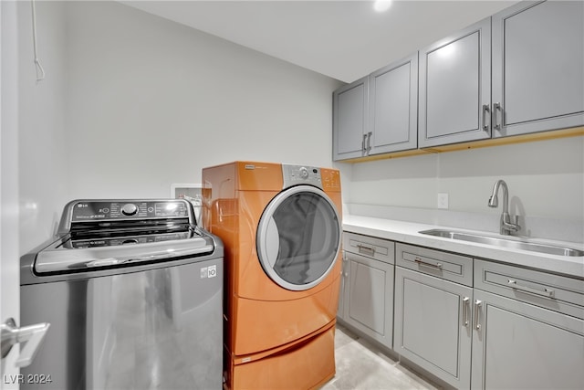 washroom featuring washing machine and clothes dryer, cabinets, and sink