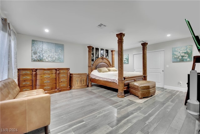 bedroom with hardwood / wood-style flooring and ornate columns