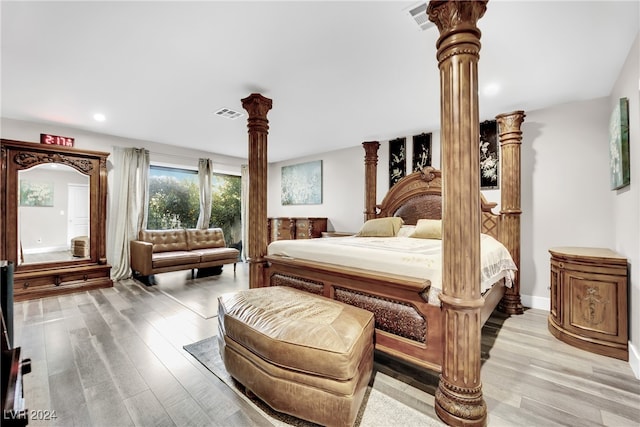 bedroom with light hardwood / wood-style flooring and decorative columns