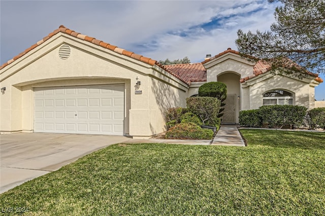 mediterranean / spanish house featuring a front yard and a garage