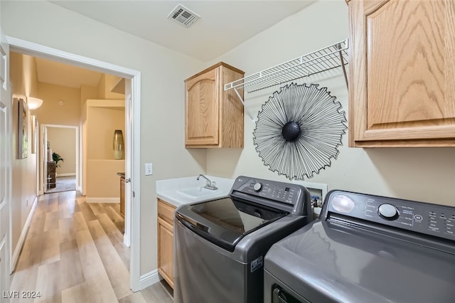 washroom featuring sink, washer and clothes dryer, light wood-type flooring, and cabinets