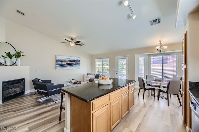 kitchen with hanging light fixtures, rail lighting, light hardwood / wood-style flooring, ceiling fan with notable chandelier, and a center island