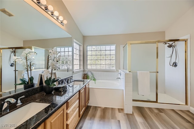 bathroom featuring vanity, independent shower and bath, hardwood / wood-style floors, and vaulted ceiling