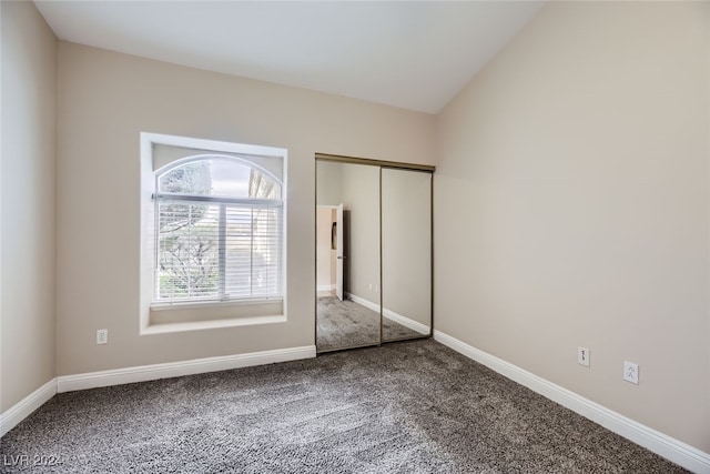 unfurnished bedroom with vaulted ceiling, carpet flooring, and a closet