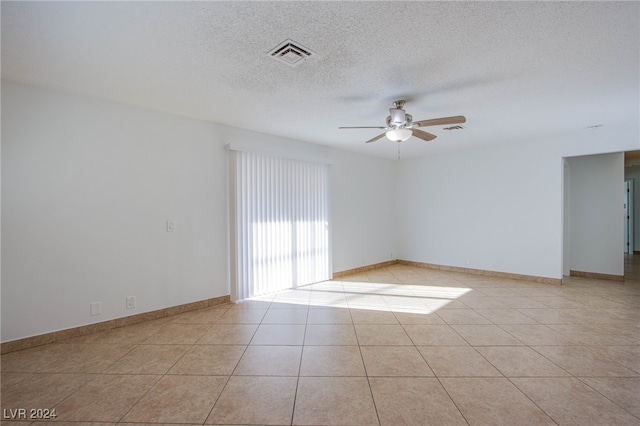 tiled empty room featuring a textured ceiling and ceiling fan