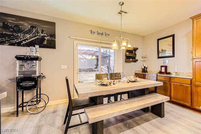 dining space with an inviting chandelier and light hardwood / wood-style flooring