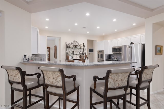 kitchen featuring appliances with stainless steel finishes, kitchen peninsula, backsplash, and white cabinets