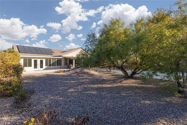 rear view of house with solar panels and a sunroom