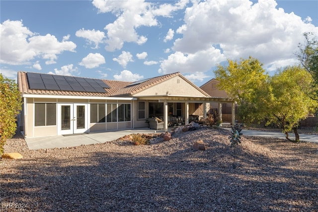 back of house with a patio, french doors, and solar panels