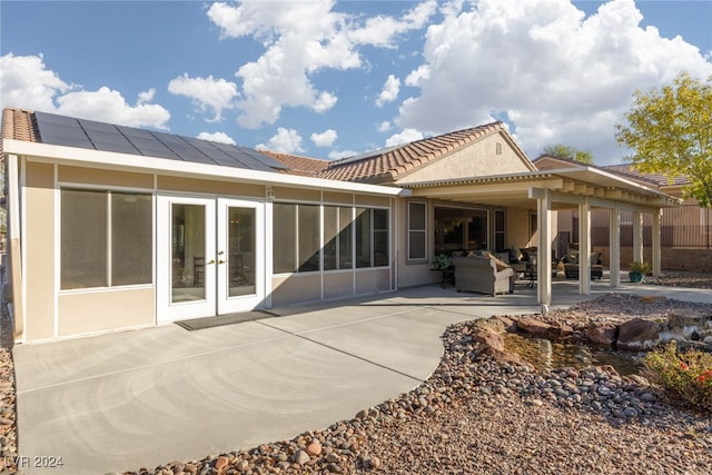 rear view of property featuring solar panels, a sunroom, a patio area, french doors, and outdoor lounge area