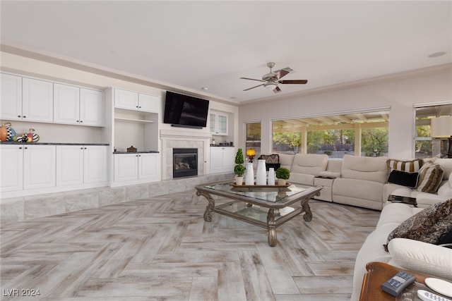 living room with crown molding, a fireplace, light parquet flooring, and ceiling fan