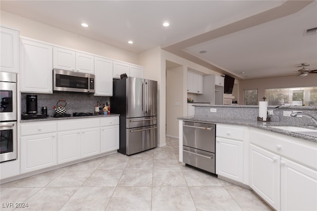 kitchen with white cabinetry, stainless steel appliances, tasteful backsplash, and ceiling fan