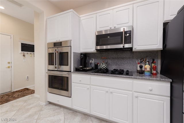 kitchen featuring white cabinetry, black appliances, light tile patterned floors, and decorative backsplash