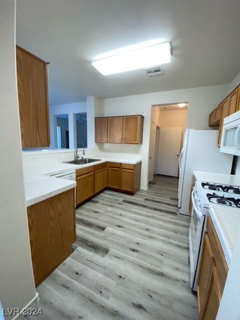 kitchen featuring sink, light hardwood / wood-style flooring, kitchen peninsula, and white appliances