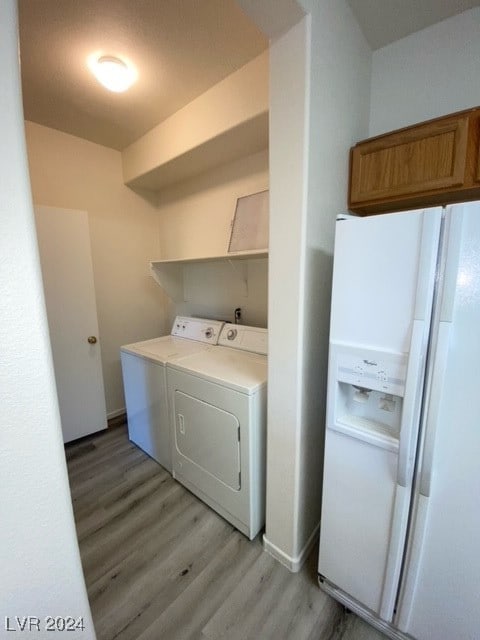 clothes washing area featuring washer and clothes dryer and light hardwood / wood-style floors