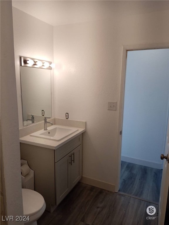 bathroom featuring toilet, vanity, and hardwood / wood-style floors