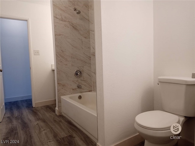 bathroom with hardwood / wood-style flooring, toilet, and tiled shower / bath