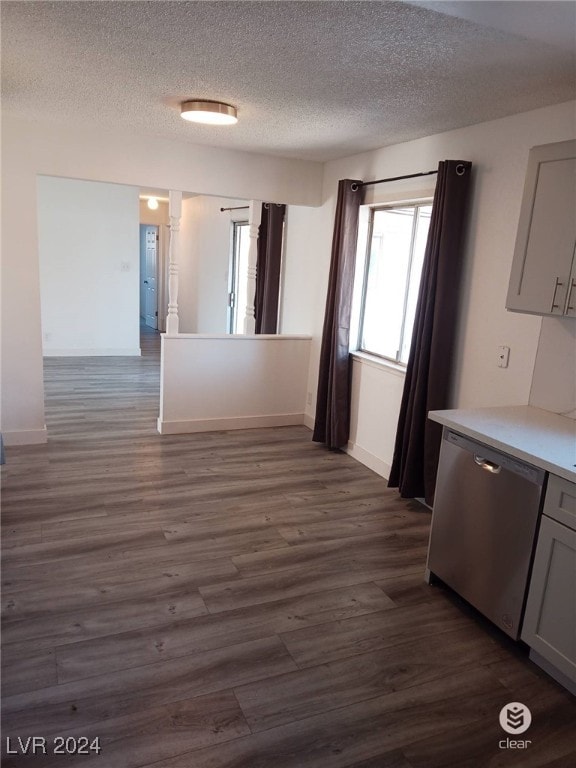 interior space with a textured ceiling, stainless steel dishwasher, and dark hardwood / wood-style floors