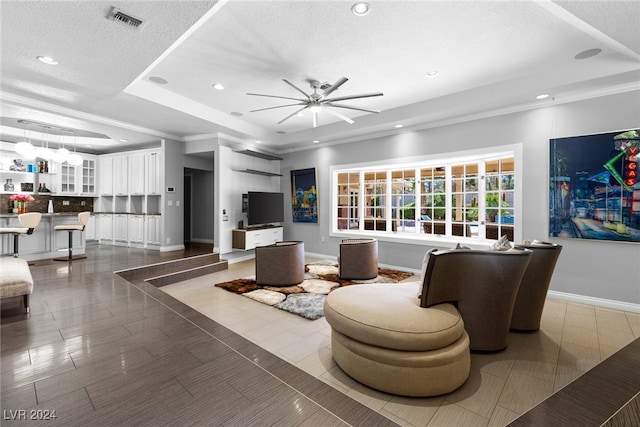 living room featuring ornamental molding, a textured ceiling, and a raised ceiling