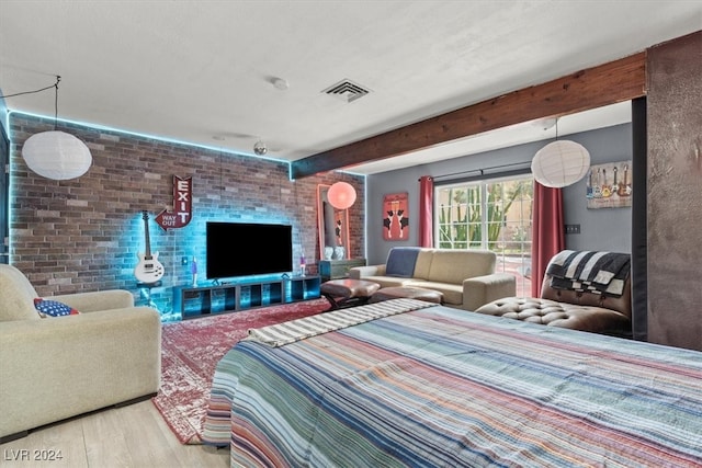 bedroom with beam ceiling, brick wall, and light wood-type flooring