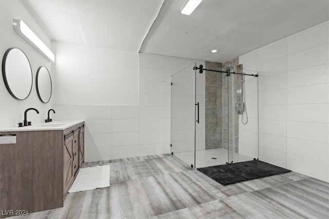 bathroom featuring vanity, a shower with shower door, wood-type flooring, and tile walls