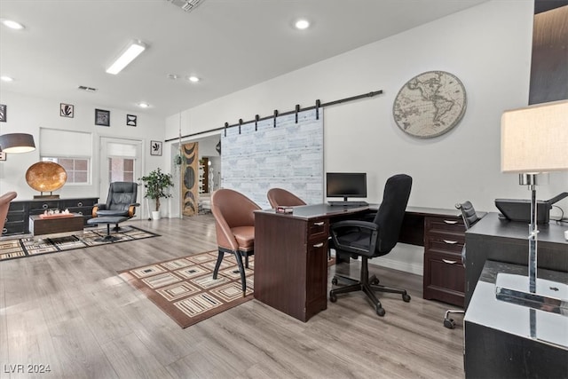 office space with a barn door and light wood-type flooring