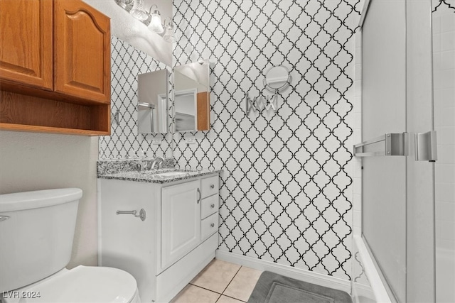 bathroom with toilet, vanity, a shower, and tile patterned flooring