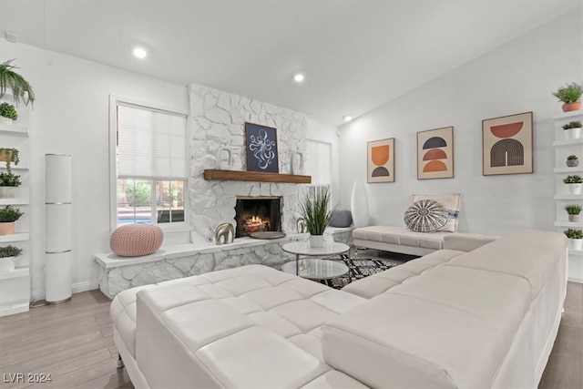 living room featuring lofted ceiling, hardwood / wood-style flooring, and a fireplace