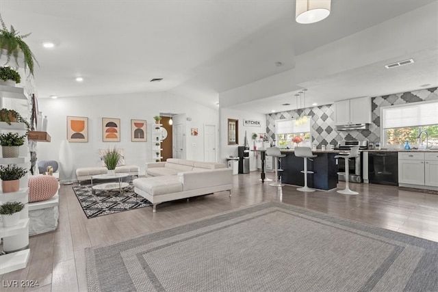 living room featuring sink, lofted ceiling, and hardwood / wood-style floors