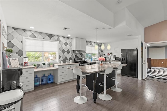 kitchen with plenty of natural light, a kitchen island, decorative light fixtures, and black fridge with ice dispenser