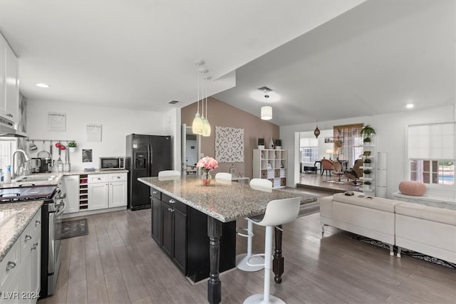 kitchen featuring a kitchen island, sink, decorative light fixtures, white cabinetry, and appliances with stainless steel finishes