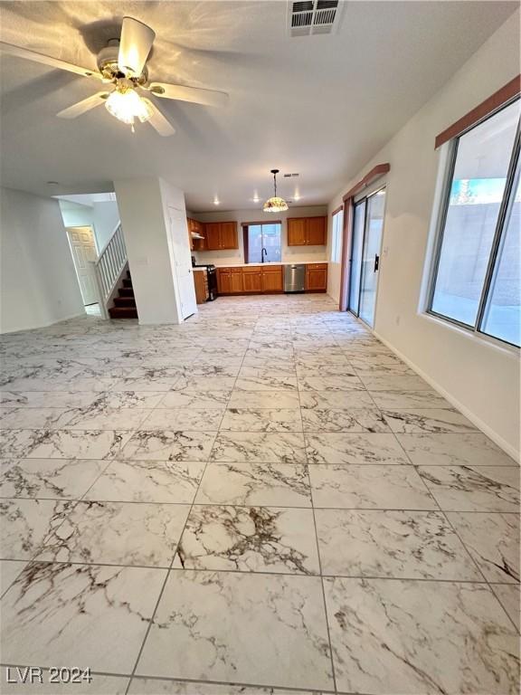 unfurnished living room featuring a wealth of natural light and ceiling fan