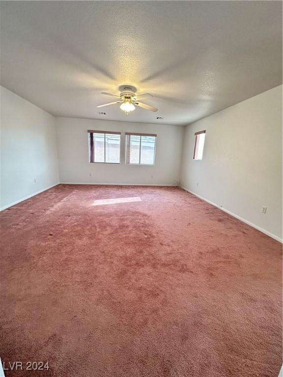 carpeted empty room featuring ceiling fan and a textured ceiling